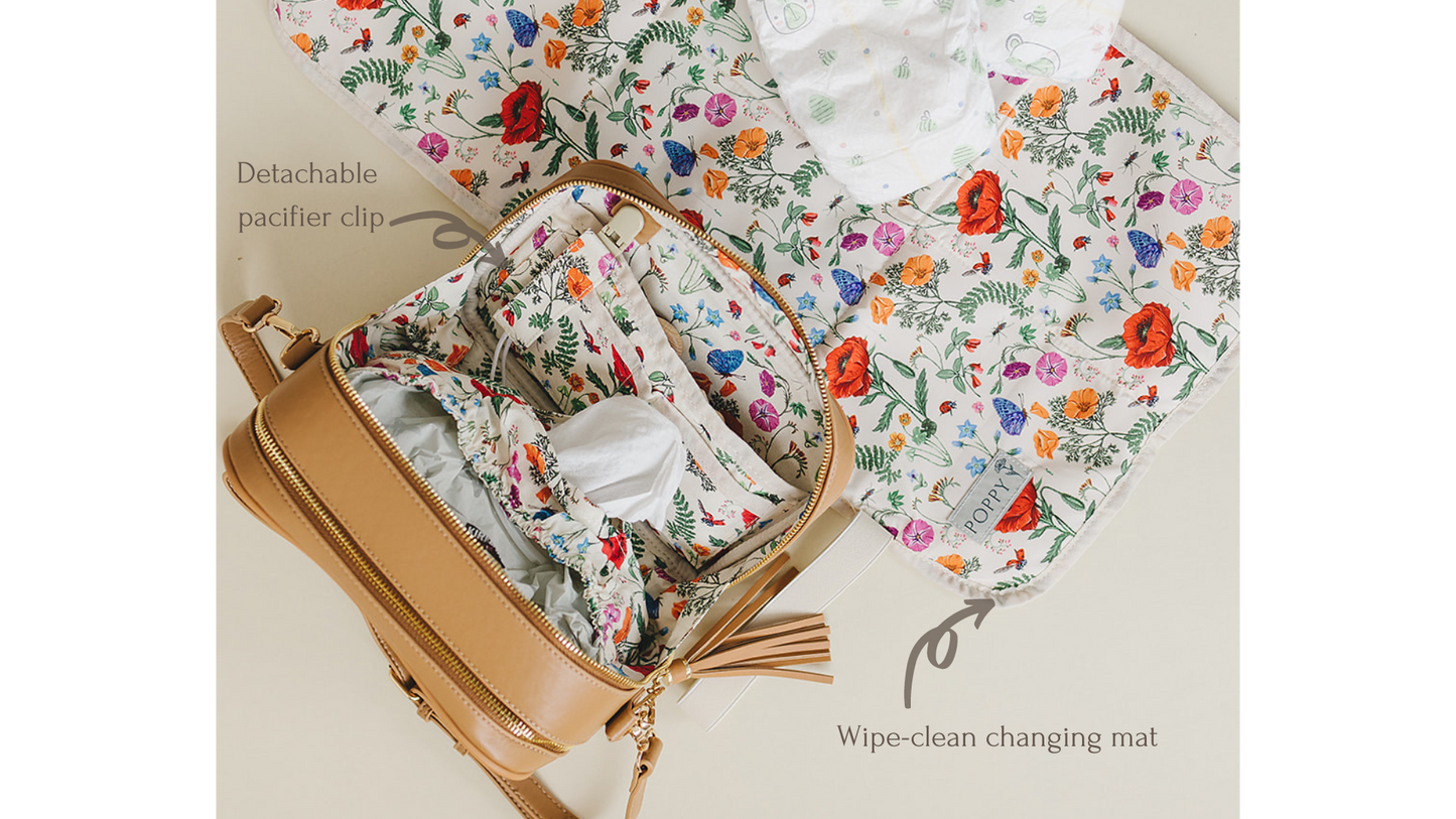 Photo of interior of the Poppy bag, highlighting the detachable pacifier clip and showing the optional wipe-clean changing mat. 